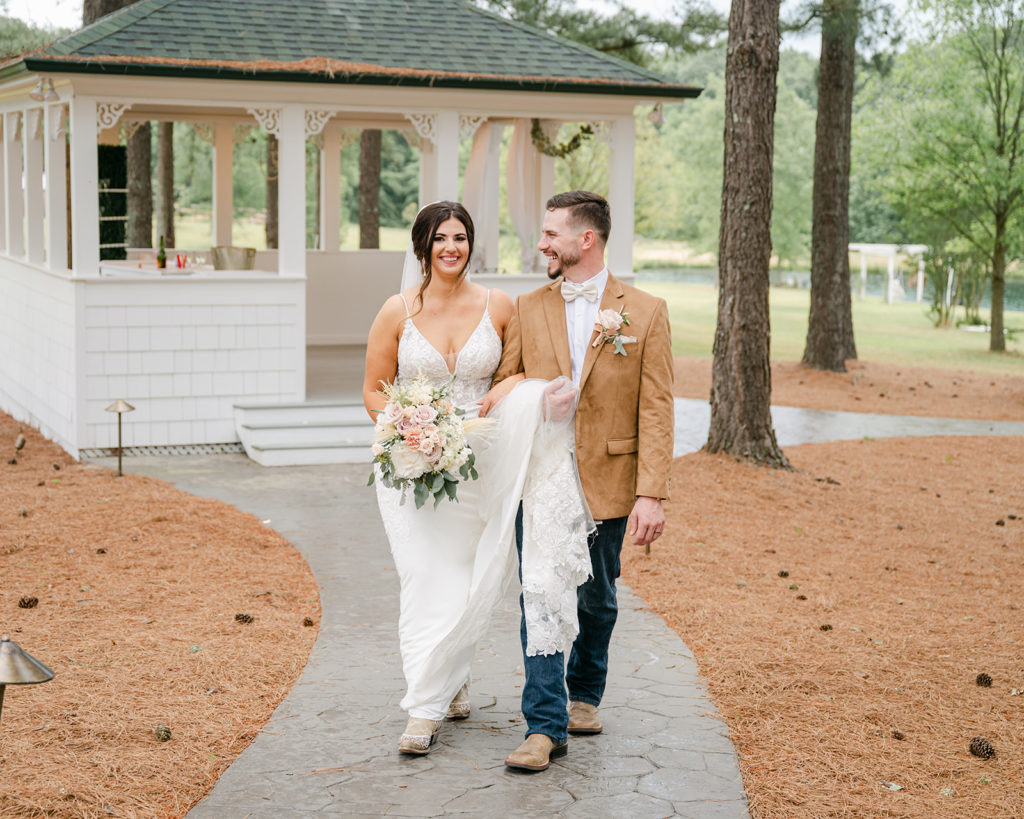 Bride and groom walking hand in hand through pine trees after their outdoor wedding ceremony in North Carolina, captured by Brandie Baird Photography.