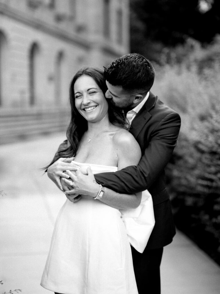 Black and white candid engagement photo of couple embracing and laughing during engagement session