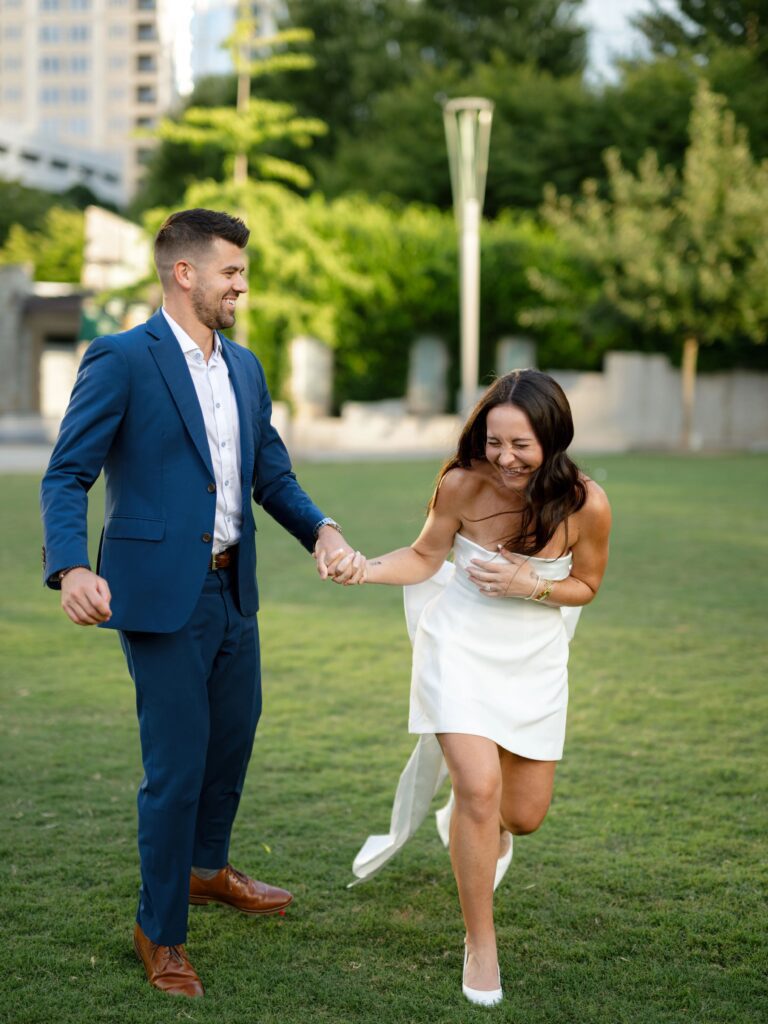 Couple laughing and running hand in hand during candid engagement session with natural movement